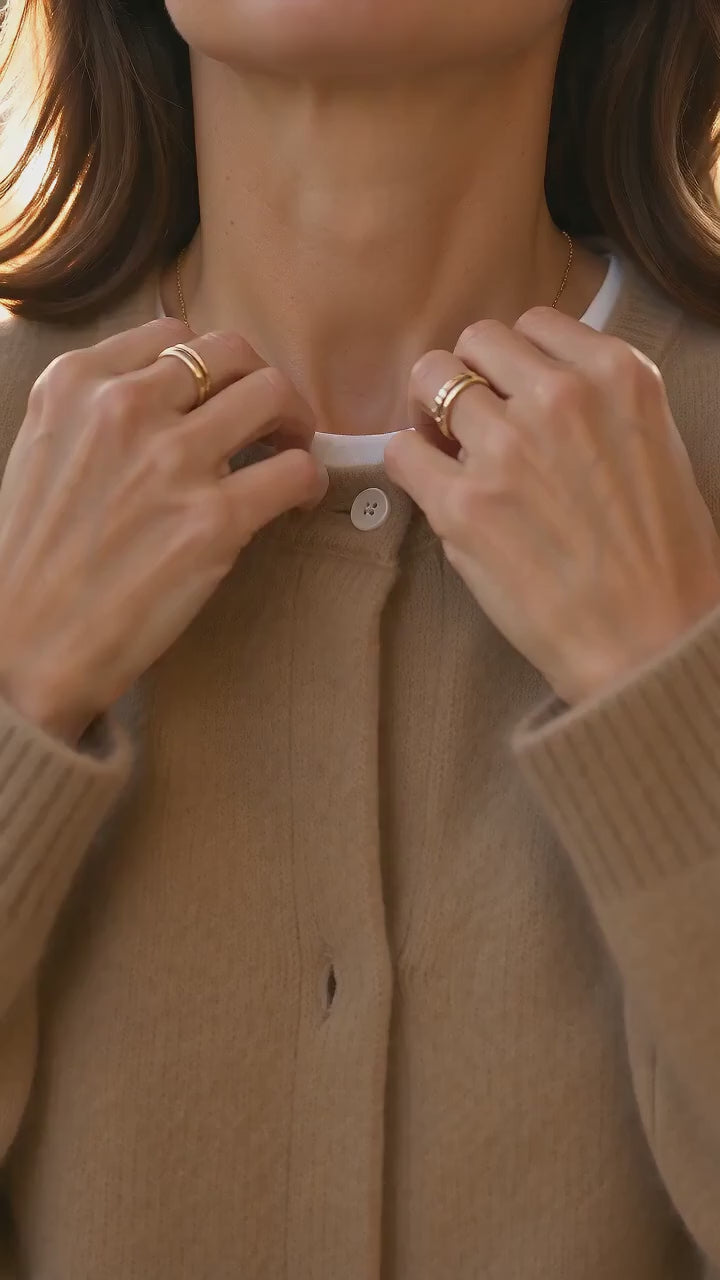 Kort film som visar elegant lång stickad kofta med knappar och långa ärmar i rörelse — passform, material och detaljer.