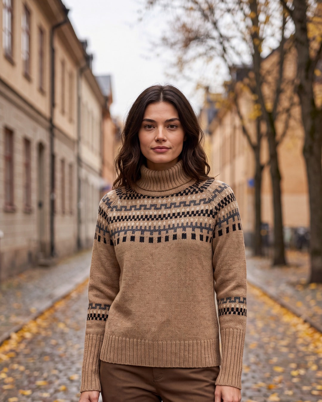 Kvinna i chunky stickad Fair Isle-tröja i camel med hög rullkrage, på en höstgata i Stockholm
