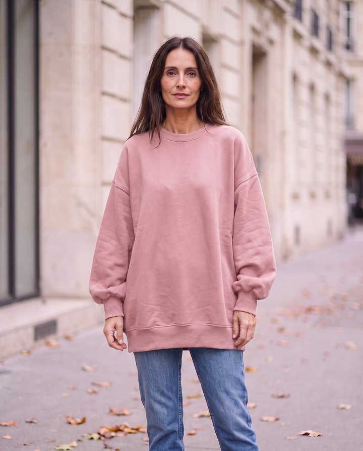 Kvinna i rosa oversized stickad tröja utan sidöppningar, framifrån