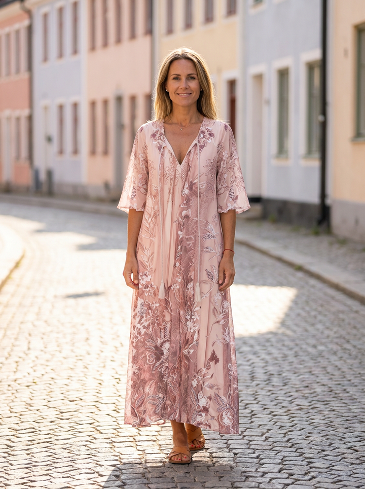 Sophie blommig maxiklänning i puderrosa med halvlånga vida ärmar, buren på solig kullerstensgata i gammal svensk stadskärna – Lissandra.se